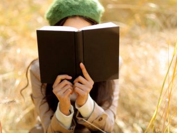 Jeune femme qui lit un livre dans un champ de blé