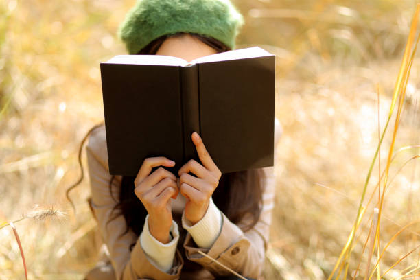 Jeune femme qui lit un livre dans un champ de blé