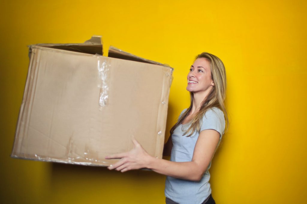 Jeune femme qui porte un gros carton de déménagement