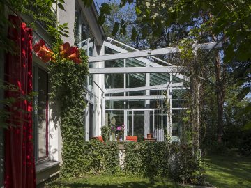 Véranda construite le long d'une maison et au beau milieu d'un jardin