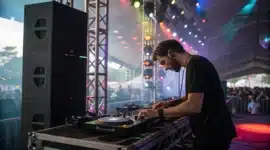 Un DJ concentré sur ses platines, entouré d’enceintes et de lumières.